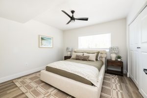 a bedroom with a ceiling fan and white walls at The Palm Haven
