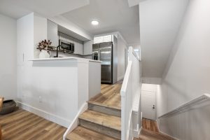 a kitchen with white cabinets and a staircase at The Palm Haven